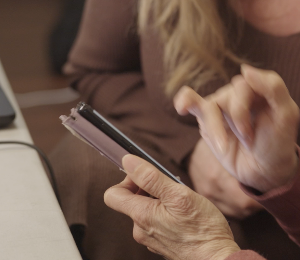 An old woman's hands, one hand holding a mobile phone and the other poised over it about to interact.