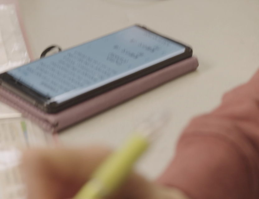 A phone kept on a counter, behind a blurred hand.