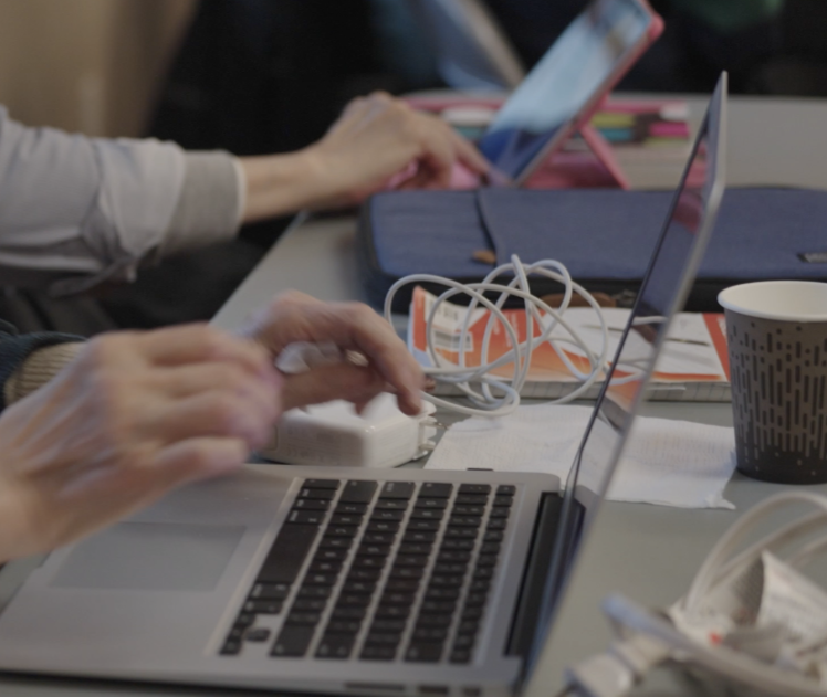 Two people's hands posied over laptops.